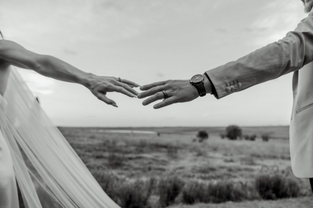 Black and white photograph of a couple exchanging vows at their wedding, capturing the emotion and elegance of the moment.