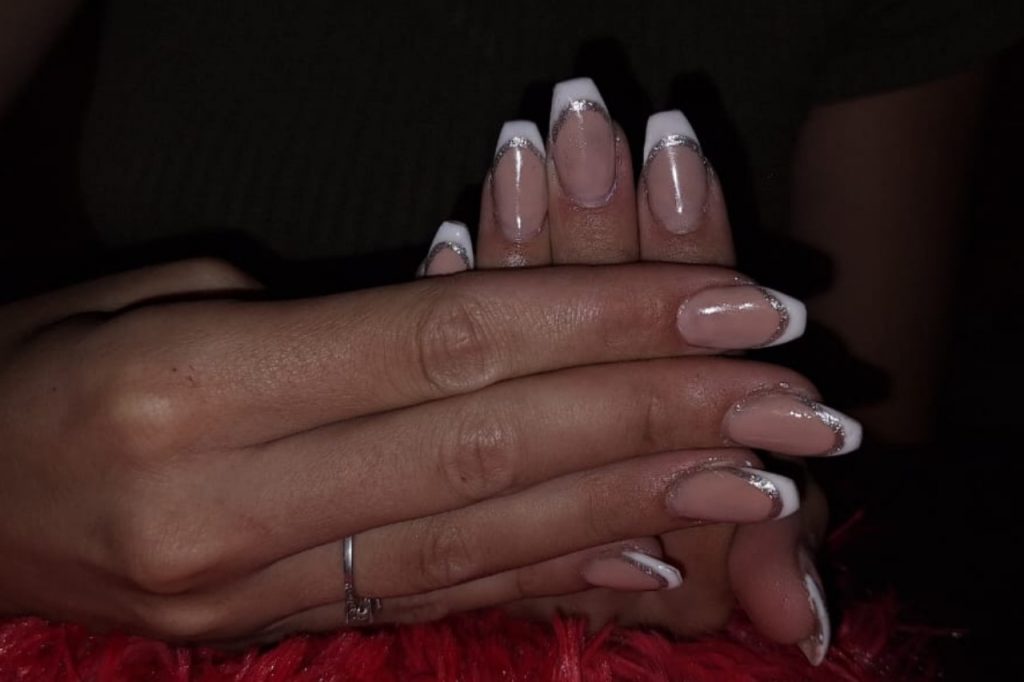 A woman showing off her long nails with elegant white tips, highlighting a stylish manicure.