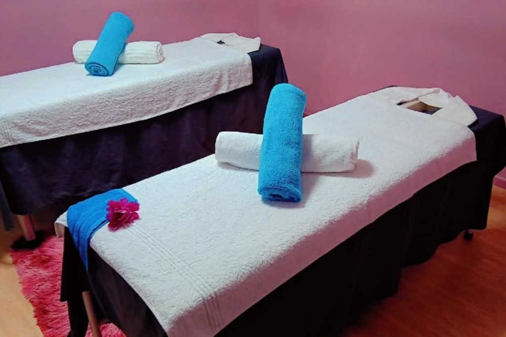 Two neatly made beds with white linens and blue towels arranged on top.