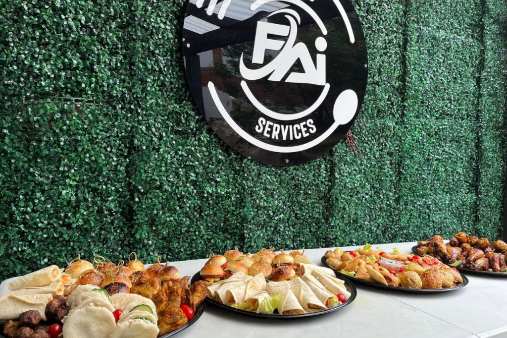 Buffet table filled with various foods, featuring a sign that reads "FAI Services" prominently displayed.