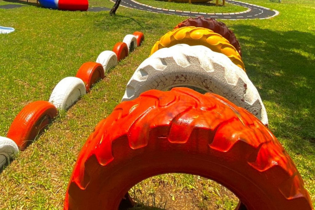 A vibrant playground featuring colorful equipment, tire tracks, and a tire swing for children to enjoy.