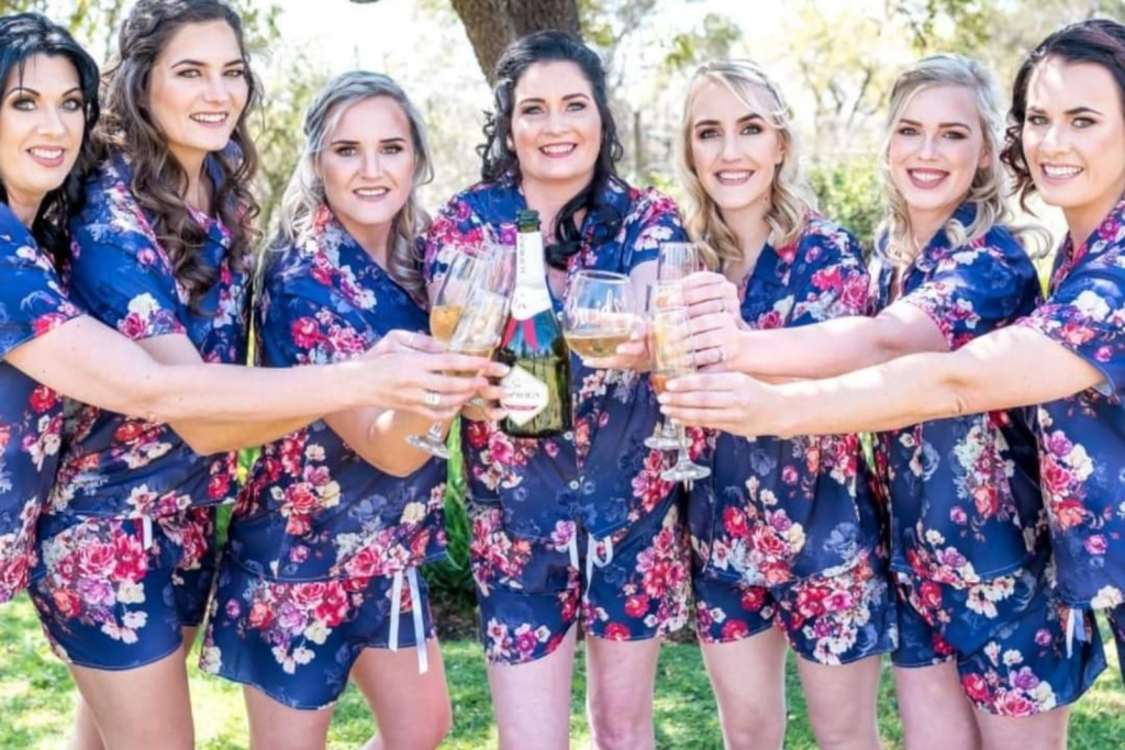 Bridesmaids in floral pajamas cheerfully toasting champagne glasses together, celebrating a special occasion.
