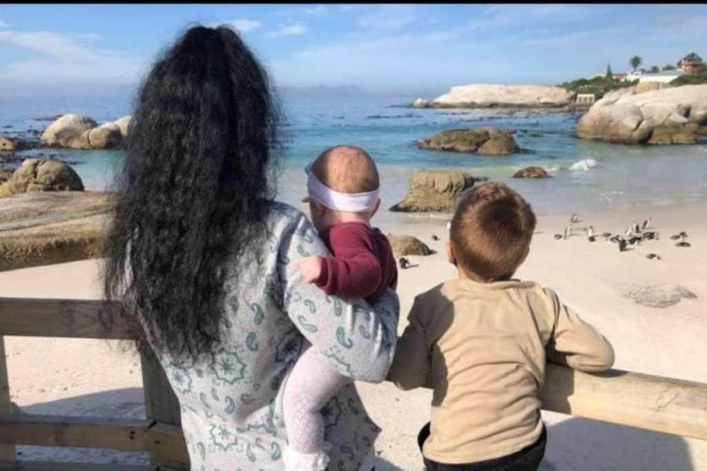 A woman and two children gaze at the ocean, enjoying a moment together by the shore.