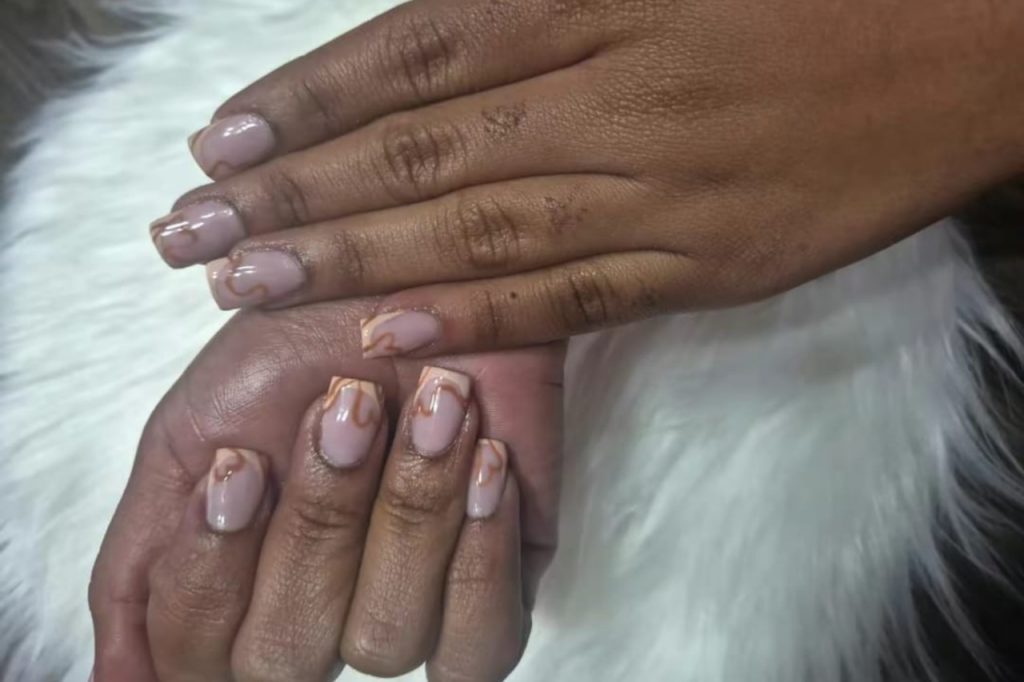 Close-up of a woman's hand with pink and gold nails, held up in a relaxed position.